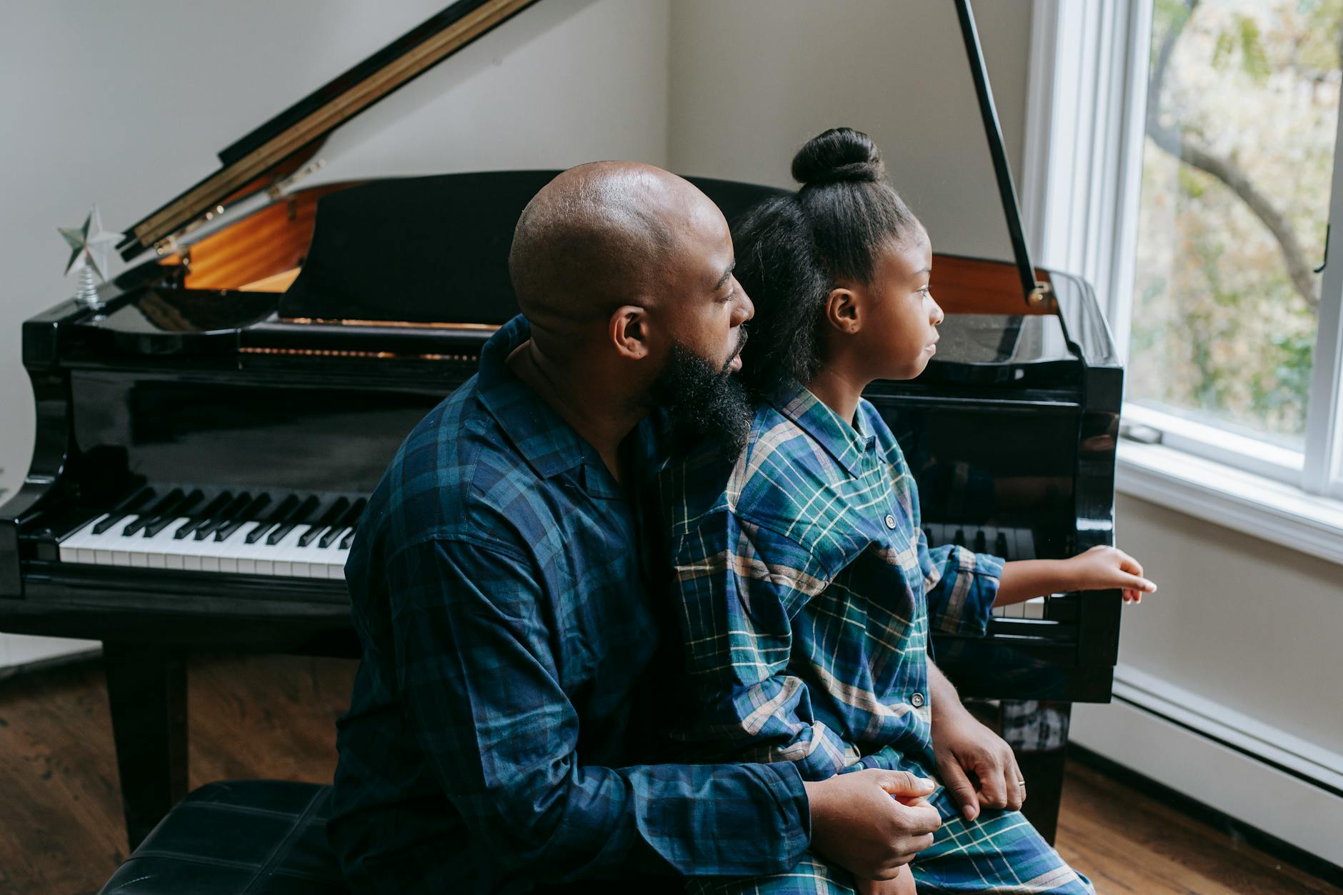black father and daughter sitting near piano at home